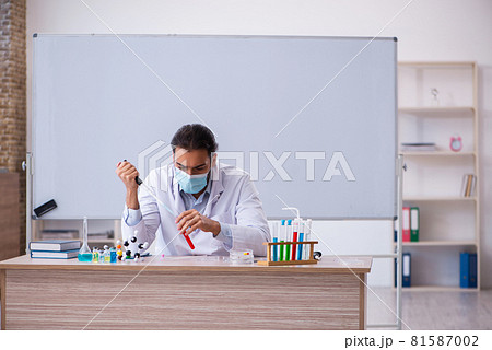 Young male chemist teacher sitting in the classroom Young male chemist teacher sitting in the classroom 81587002