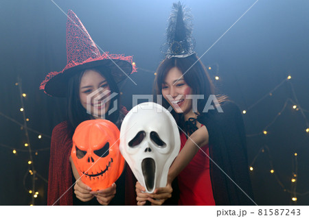 Portrait of two beautiful young woman in witch halloween costumes at party over dark magic background - Halloween party concept Portrait of two beautiful young woman in witch halloween costumes at party over dark magic background - Halloween party concept 81587243
