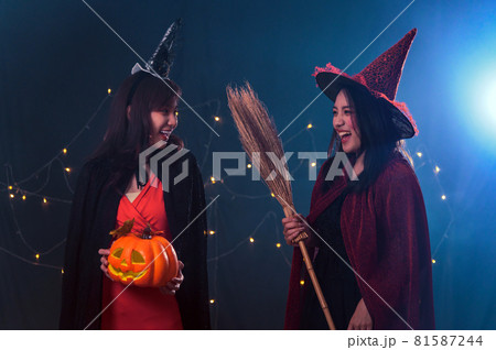 Portrait of two beautiful young woman in witch halloween costumes at party over dark magic background - Halloween party concept Portrait of two beautiful young woman in witch halloween costumes at party over dark magic background - Halloween party concept 81587244
