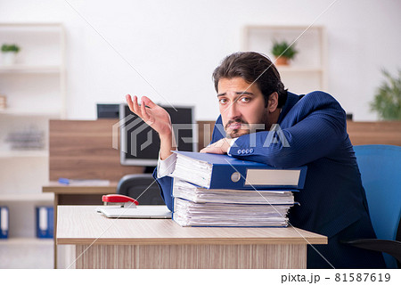 Young male employee and too much work in the office 81587619