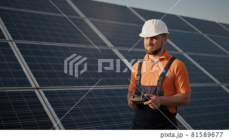 Industrial expert wearing helmet and controlling drone in photovoltaic solar power plant. Solar panel array installation. Technologies and ecology. New technologies 81589677