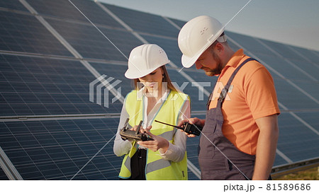 Technician and investor Using Infrared Drone Technology to Inspect Solar Panels in Solar cell Farm. Engineer woman in hardhat holding tablet computer operating flying drone in solar plant Technician and investor Using Infrared Drone Technology to Inspect Solar Panels in Solar cell Farm. Engineer woman in hardhat holding tablet computer operating flying drone in solar plant 81589686
