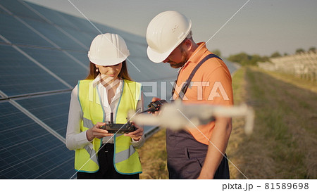 Portrait of a female engineer operating a drone on the background of a solar power plant. Photovoltaic solar panel installation. Solar array. New technologies. Investor and worker engineer Portrait of a female engineer operating a drone on the background of a solar power plant. Photovoltaic solar panel installation. Solar array. New technologies. Investor and worker engineer 81589698
