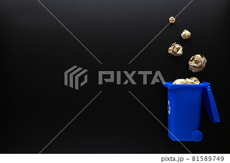 Recycled paper. Blue dustbin for recycle plastic and glass can trash on black background. Bin container for disposal garbage waste and save environment. Copy space. Recycled paper. Blue dustbin for recycle plastic and glass can trash on black background. Bin container for disposal garbage waste and save environment. Copy space. 81589749