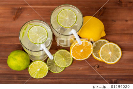 Two refreshing glasses of cold fruit juice with straw, ice lime and lemon juice, decorating with fresh lime and lemon on wooden table. Concept for refreshing Two refreshing glasses of cold fruit juice with straw, ice lime and lemon juice, decorating with fresh lime and lemon on wooden table. Concept for refreshing 81594020