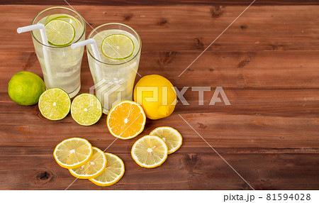 Two refreshing glasses of cold fruit juice with straw, ice lime and lemon juice, decorating with fresh lime and lemon on wooden table. Concept for refreshing Two refreshing glasses of cold fruit juice with straw, ice lime and lemon juice, decorating with fresh lime and lemon on wooden table. Concept for refreshing 81594028