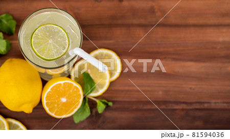 A refreshing glass of cold lime juice with ice and straw, decorating the glasses with lime slice. Fresh lime, lemon both cut and slice and mint leaf are on wooden table. Healthy concept A refreshing glass of cold lime juice with ice and straw, decorating the glasses with lime slice. Fresh lime, lemon both cut and slice and mint leaf are on wooden table. Healthy concept 81594036
