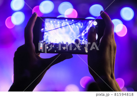 Woman hands recording video of live music concert with smartphone at night Woman hands recording video of live music concert with smartphone at night 81594818