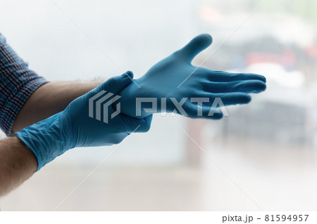 Hands of man putting on blue latex rubber gloves 81594957