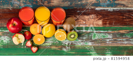 Different fruits juice in glass, apple, orange and strawberry juice, looking refreshing on colourful wood board. Picture decorating with fresh fruits Different fruits juice in glass, apple, orange and strawberry juice, looking refreshing on colourful wood board. Picture decorating with fresh fruits 81594958