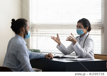 Focused young indian doctor talking with african patient. 81595716
