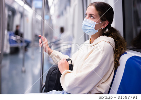 Pensive girl in a protective mask on a subway train goes on business 81597791