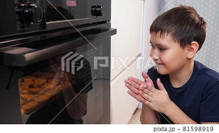 boy sits and looks into the oven while waiting for a cookie boy sits and looks into the oven while waiting for a cookie 81598919