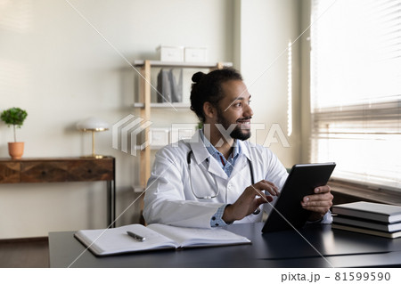 Dreamy young african american doctor using digital tablet. Dreamy young african american doctor using digital tablet. 81599590