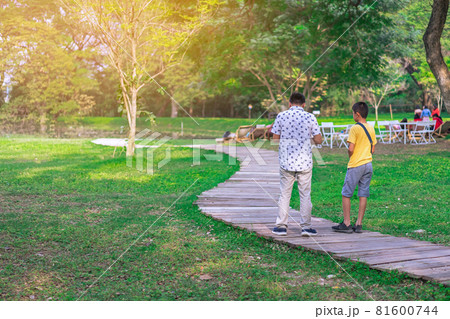 Back view of Asian father and son walking on pathway through green garden.Dad and son walking together in park. Happy family spending time together outside in green nature. Family time concept. 81600744