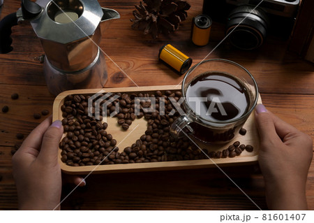 Woman holding wooden tray with cup of coffee and roasted coffee beans. 81601407