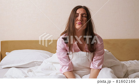 Sleeping dark haired woman in pajama rises quickly upset Sleeping dark haired woman in pajama rises quickly upset 81602166