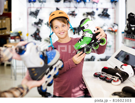 Male shop assistant helping boy to choose roller-skates in sports store Male shop assistant helping boy to choose roller-skates in sports store 81602303