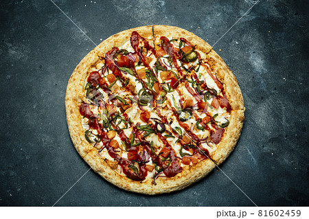 Pizza on a dark background. Classic italian pizza with tomatoes, pepper, vegetables, sauce and mazarella cheese on a dark kitchen table. Copy space Pizza on a dark background. Classic italian pizza with tomatoes, pepper, vegetables, sauce and mazarella cheese on a dark kitchen table. Copy space 81602459
