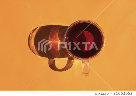 a mug of tea with a hard shadow on an orange background 81603052