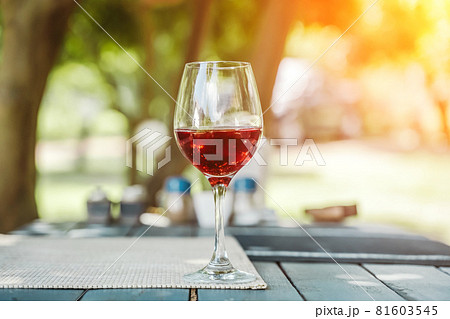 A glass of red wine on the table of a street cafe a sunny summer day. Summer, lifestyle, relaxation, and enjoyment concept. A glass of red wine on the table of a street cafe a sunny summer day. Summer, lifestyle, relaxation, and enjoyment concept. 81603545