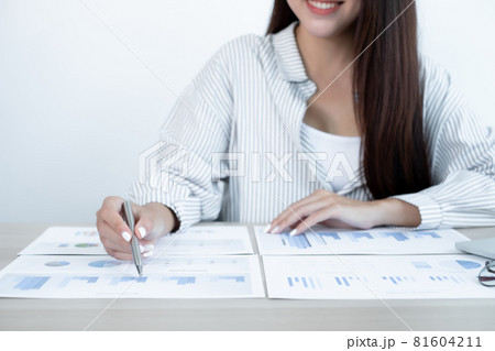 Asian female accountant sits at their desks and calculates financial graphs showing results about their investments, plan a successful business growth process 81604211