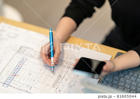 携帯を見ながら図面を書く女性一級建築士 81605044