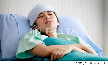 An asian young beautiful female patient getting sick, lying and sleeping on bed in hospital with cool pack on her forehead to relieve the fever. Medical Treatment and Health concept. 81607261