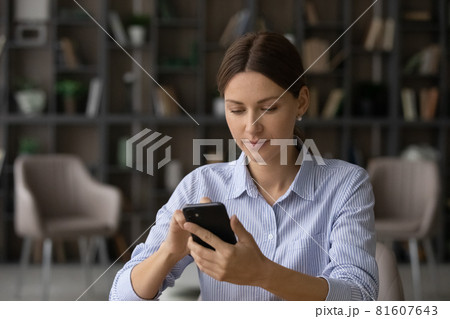 Focused businesswoman looking at phone screen, browsing mobile device apps Focused businesswoman looking at phone screen, browsing mobile device apps 81607643