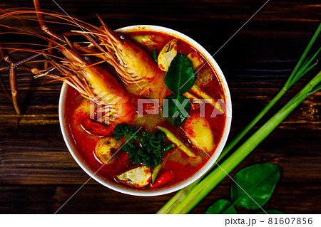 Top view shot of Fresh delicious tasty Tom Yam Kung hot sweet sour spicy Thai shrimp prawn mushrooms and herb soup in white bowl on sack cloth with ingredients spring onion lemon basil on wood table Top view shot of Fresh delicious tasty Tom Yam Kung hot sweet sour spicy Thai shrimp prawn mushrooms and herb soup in white bowl on sack cloth with ingredients spring onion lemon basil on wood table 81607856