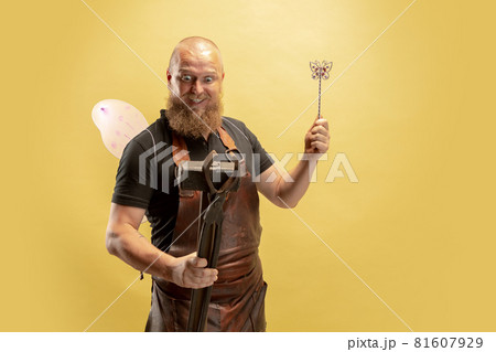Comic portrait of muscular bearded bald man, blacksmith in leather apron or uniform isolated on yellow studio background. Concept of labor, retro professions, power, strength, humor Comic portrait of muscular bearded bald man, blacksmith in leather apron or uniform isolated on yellow studio background. Concept of labor, retro professions, power, strength, humor 81607929
