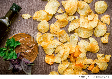 Potato chips with dipping sauce on a wooden table. Unhealthy food on a wooden background. Potato chips with dipping sauce on a wooden table. Unhealthy food on a wooden background. 81608521