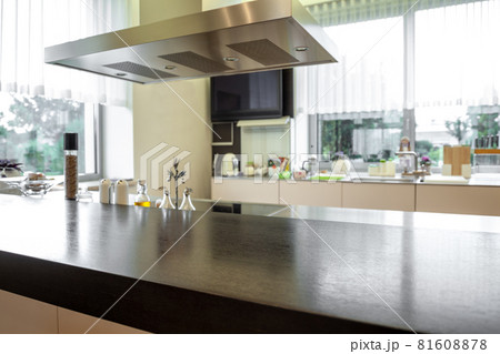 Wooden tabletop and cooker hood on blurred background of kitchen interior Wooden tabletop and cooker hood on blurred background of kitchen interior 81608878