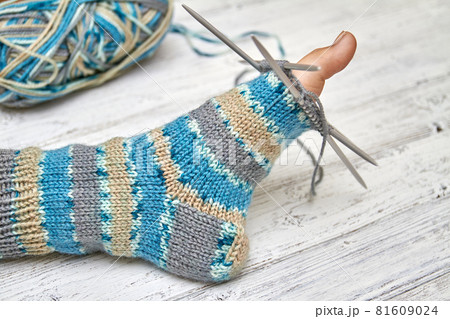 Try on sock on a baby foot while knitting. Light wooden background, selective focus 81609024
