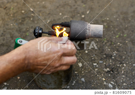 A man kindles a flame at the old rusty blowtorch. A man kindles a flame at the old rusty blowtorch. 81609075