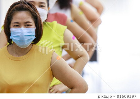 Group of diverse female stnad in row line show their colorful plaster on shoulder together after vaccinating in blurred background 81609397