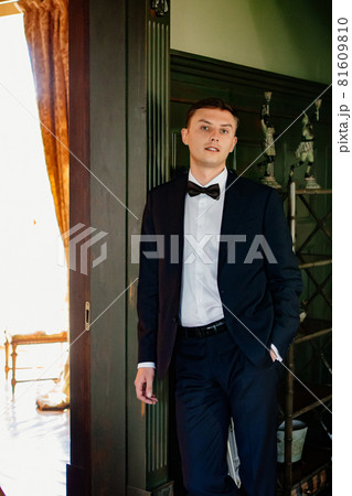 a man in a business suit with a bow tie stands at the wall a man in a business suit with a bow tie stands at the wall 81609810