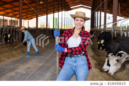 Smiling young woman cow breeder standing in cowshed 81609820