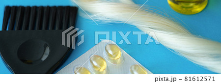 Vitamins and hair oil together with brush lie on dove background 81612571