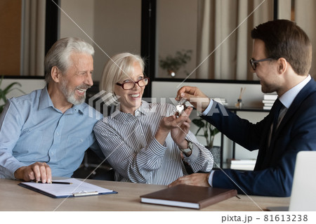 Businessman manager giving keys to excited mature couple at meeting Businessman manager giving keys to excited mature couple at meeting 81613238