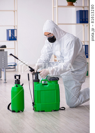 Young male contractor disinfecting office during pandemic Young male contractor disinfecting office during pandemic 81613280