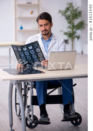 Young male doctor in wheel-chair working in the clinic Young male doctor in wheel-chair working in the clinic 81613340