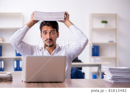 Young male employee and too much work in the office Young male employee and too much work in the office 81613482