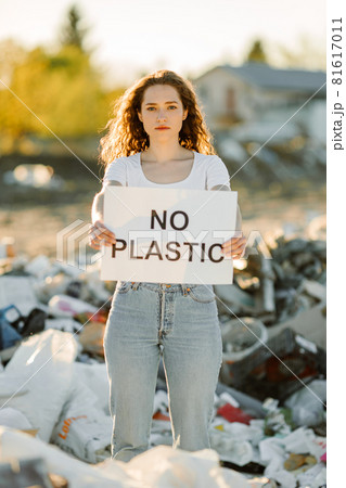 Young woman holding no plastic sign on trash place 81617011
