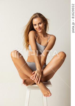 Full-length portrait of young caucasian woman in gray inner wear isolated over light studio background 81620032