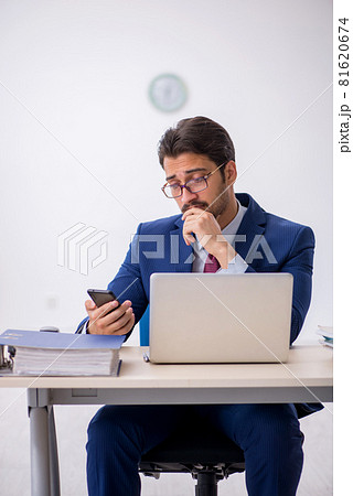 Young male employee sitting at workplace Young male employee sitting at workplace 81620674