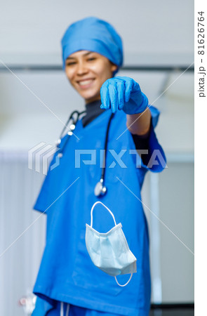 Portrait closeup shot of used surgical face mask dumped drop from happy pretty female freedom doctor hand in blue hospital suit hat with stethoscope smiling look at camera while covid pandemic end Portrait closeup shot of used surgical face mask dumped drop from happy pretty female freedom doctor hand in blue hospital suit hat with stethoscope smiling look at camera while covid pandemic end 81626764