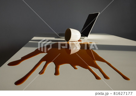 Cup of black coffee spilled on laptop on white desktop. Cup of black coffee spilled on laptop on white desktop. 81627177