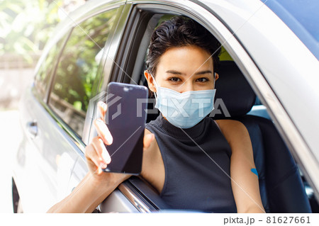 Closeup shot of blank screen mobile phone for application appointment registration copy space in female hand wearing face mask sitting in car in drive through line for coronavirus vaccination 81627661