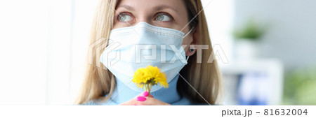 Young woman in protective medical mask sniffing yellow flower 81632004